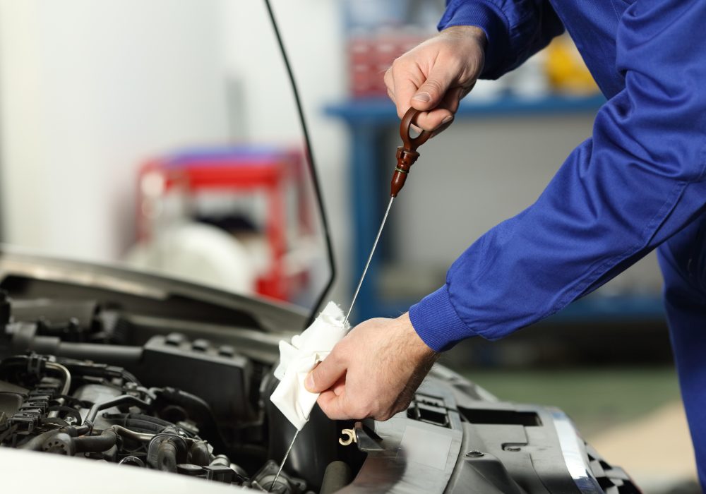 Close up of a car mechanic checking oil level in a mechanical workshop
